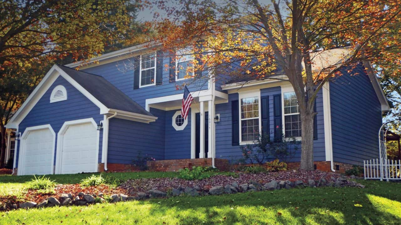 Two-story blue house with white trim and landscaped front yard.