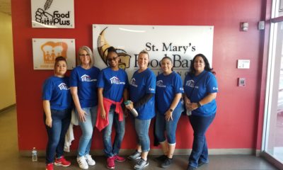 A group of women with matching blue tee shirts posing for picture inside St. Mary's Food Bank.