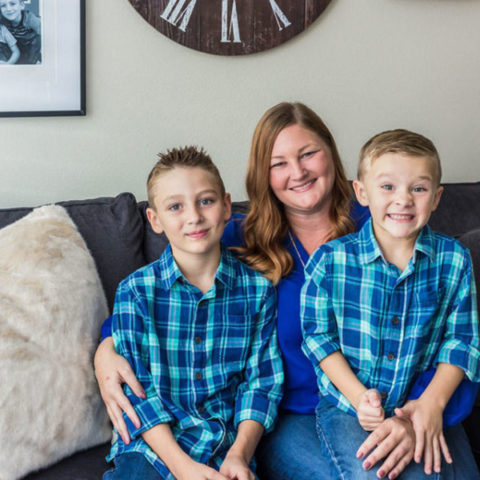 A mom and two young boys sitting on couch.