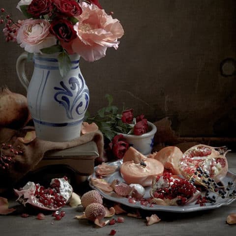 Still life artwork of vase of flowers and pomegranates.
